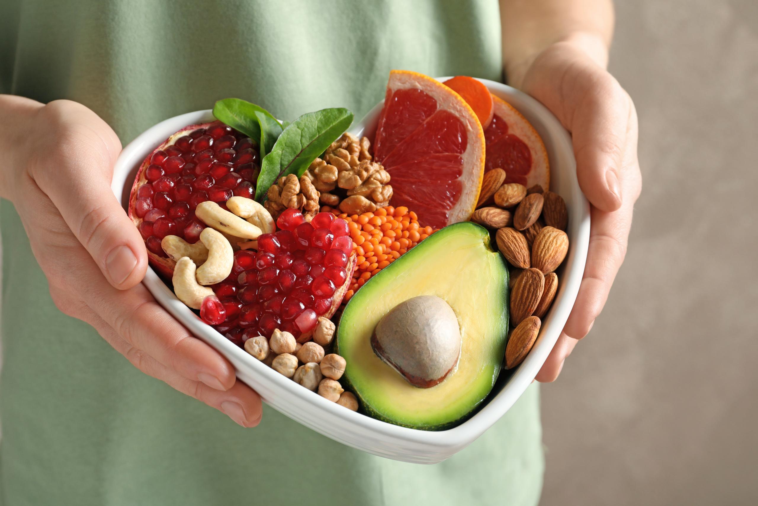 Woman holding bowl with products for heart-healthy diet, closeup