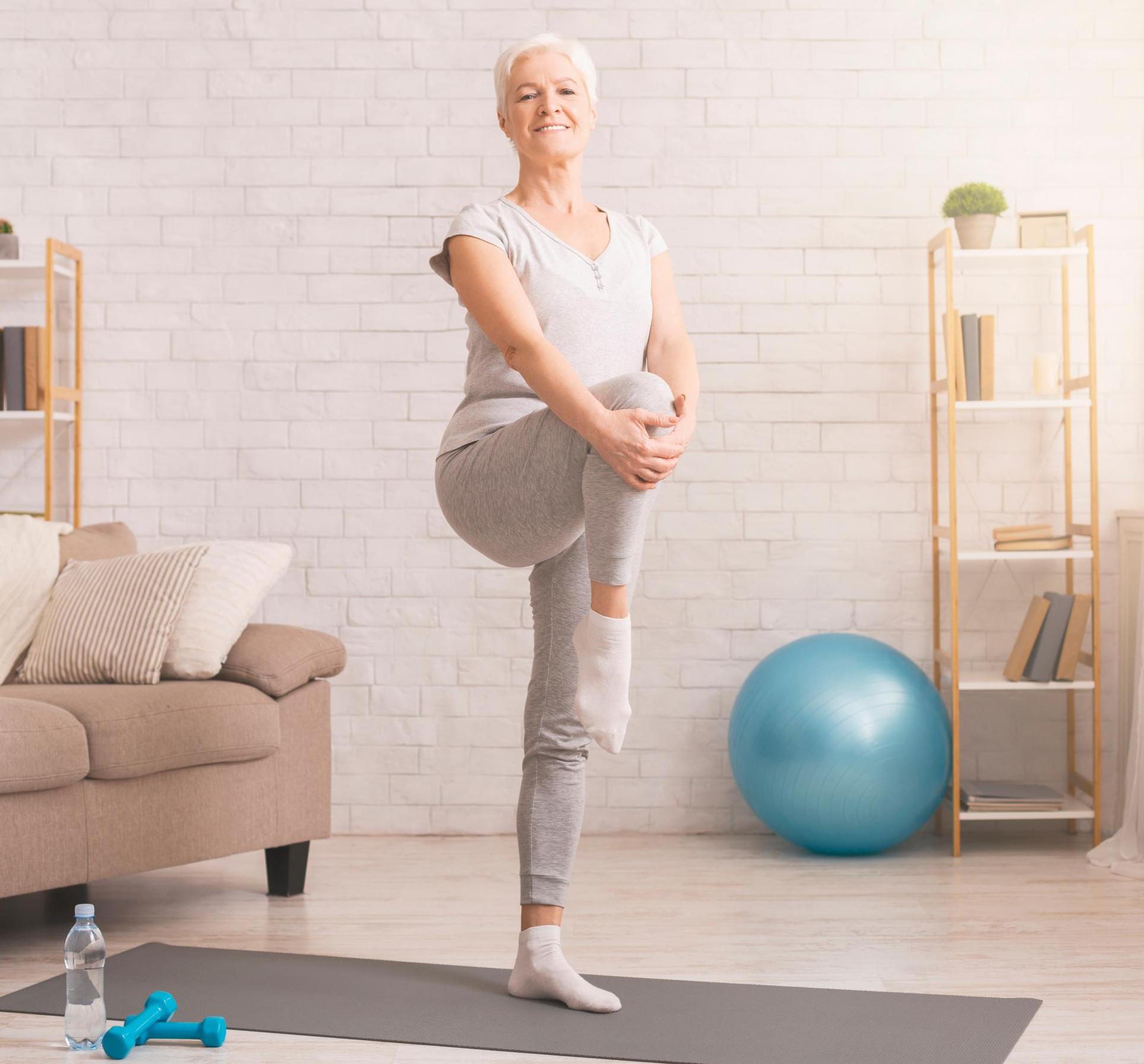 Healthy lifestyle. Active senior woman warming up at home, free space